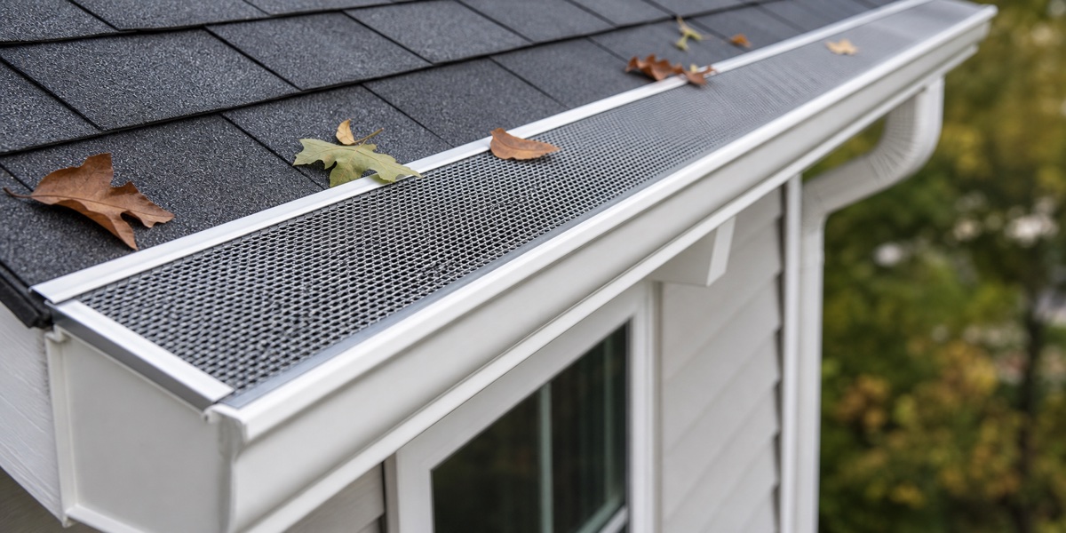 gutter guard installed over a white gutter near leaves